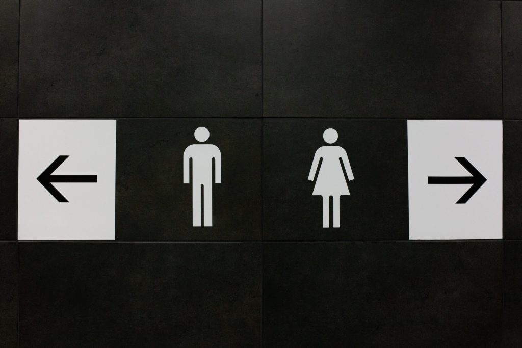 Black and white "Men's" and "Women's" bathroom signs, flanked by arrows pointing right and left.